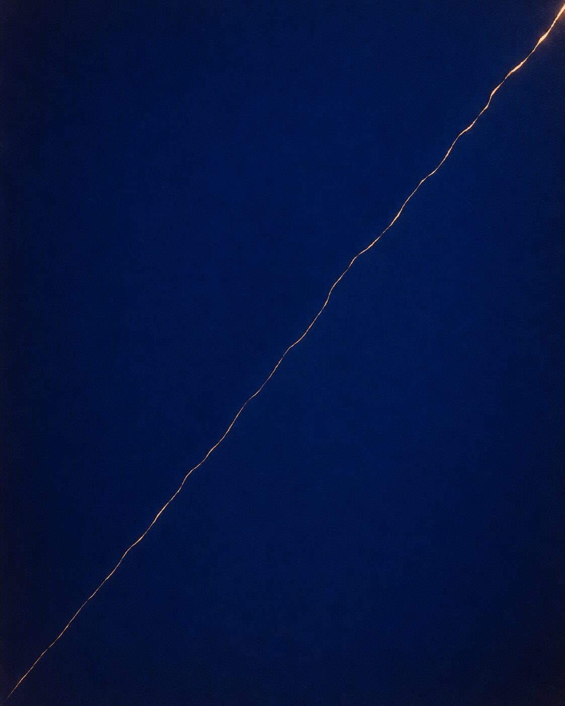 A deep ultramarine field crossed by a single thin line of warm light running diagonally.